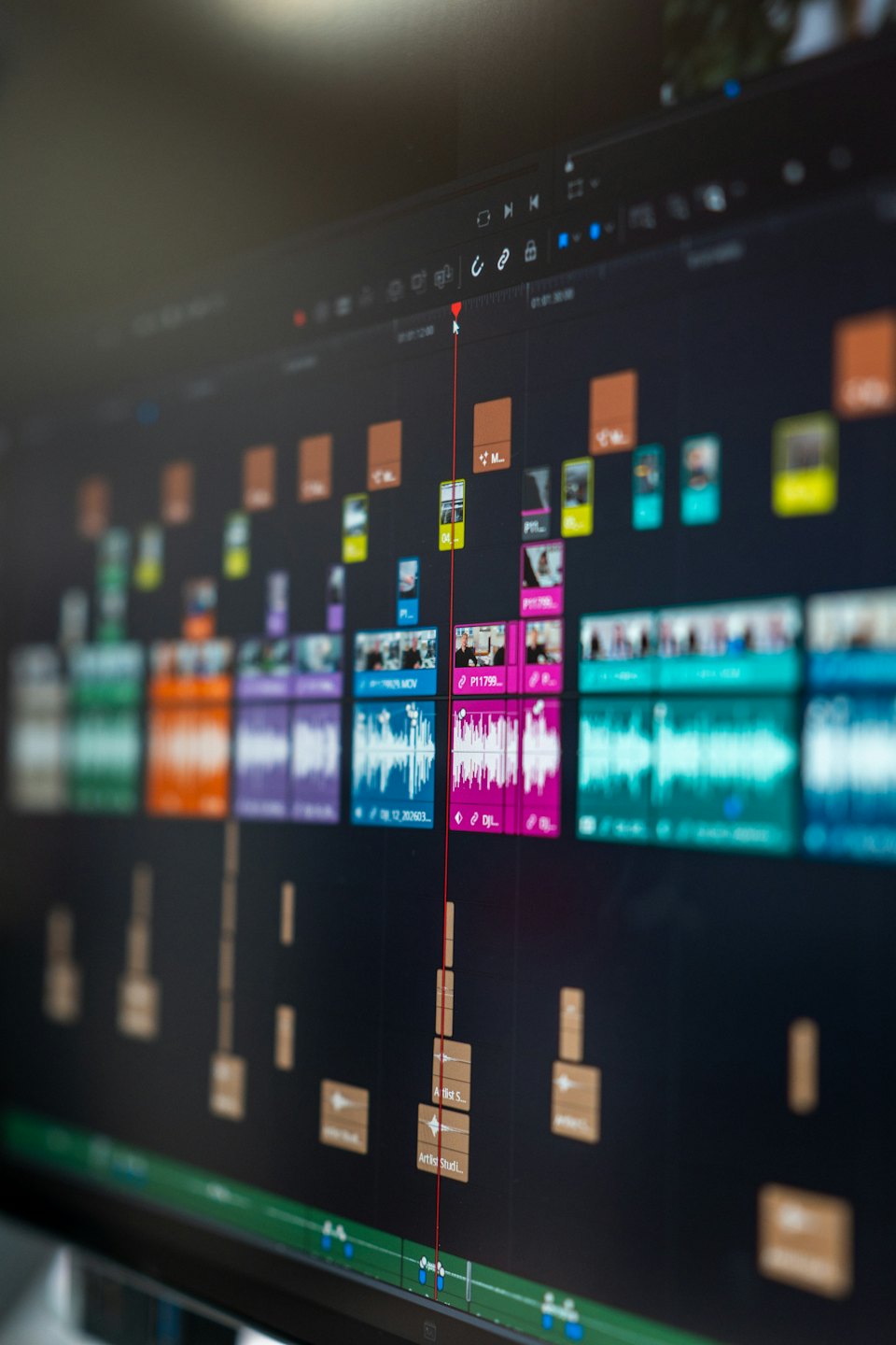 Computer monitor displays video editing software timeline with clips and waveforms.