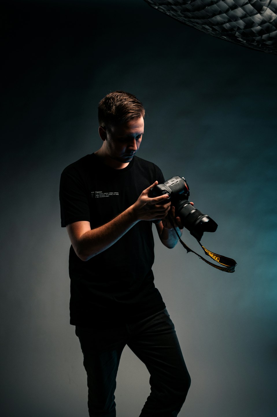 Photographer adjusts camera with a long lens in a studio.